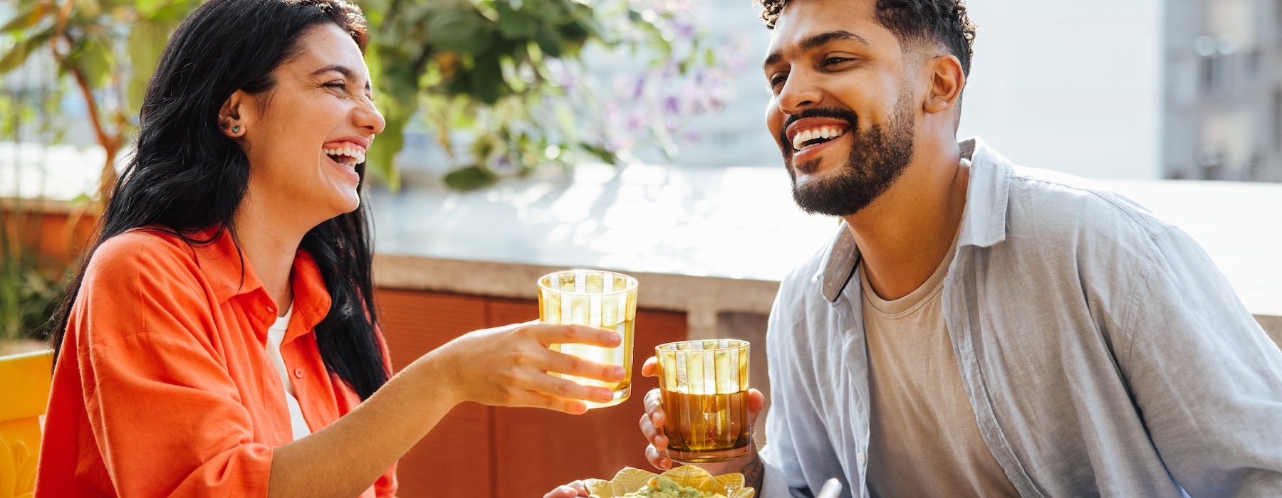 a man and woman sitting at a table with food and drinks